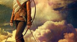 katniss stands on a hill with a bow